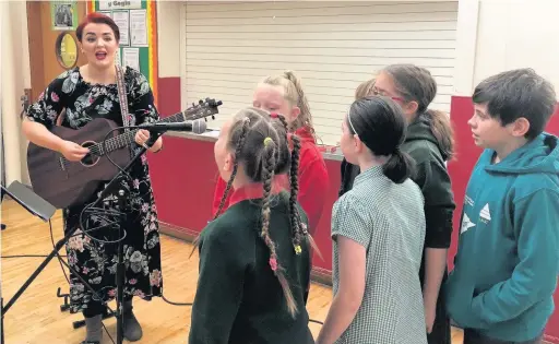  ?? ABBY BOLTER ?? Welsh singer songwriter Bronwen Lewis performing for and with pupils at Ysgol Gymraeg Bro Ogwr in Brackla, Bridgend