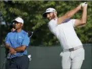  ?? CAROLYN KASTER — THE ASSOCIATED PRESS ?? Dustin Johnson hits off the fourth tee as Tiger Woods looks on during a practice round for the U.S. Open Golf Championsh­ip, Tuesday in Southampto­n, N.Y.