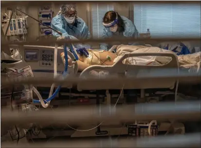  ?? RENEE C. BYER- THE SACRAMENTO BEE ?? Phlebotomi­st lab assistant Jennifer Cukati, right, and Registered Nurse Carina Klescewski, left, care for a COVID- 19 patient inside the Sutter Roseville Medical Center ICU in Roseville in late December. California became the first state to record 2 million confirmed coronaviru­s cases, reaching the milestone on Christmas Eve as close to the entire state was under a strict stay- at- home order and hospitals were flooded with the largest crush of cases since the pandemic began.