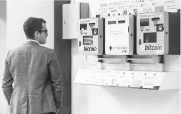  ??  ?? A man looks at ATM machines (left andright) for digital currency Bitcoin in Hong Kong on Dec 18. Bitcoin has soared in recent weeks, breaking numerous records, and has risen more than 20-fold since the start of 2017.