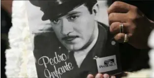  ??  ?? GREGORY BULL — ASSOCIATED PRESS, FILE In this April 15, 2007 file photo, a woman holds a photo of Pedro Infante during a visit to his grave, in Mexico City. Infante, considered one of the greatest actors of the Golden Age of Mexican cinema, died in 1957 in a plane crash at the age of 39.