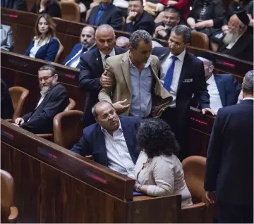  ?? (Reuters) ?? JAMAL ZAHALKA, an Arab lawmaker from the Joint Arab List, is escorted out of the Knesset after he made comments during a speech by Prime Minister Benjamin Netanyahu in 2015.