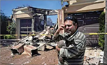  ?? MARCIO JOSE SANCHEZ / AP ?? Sassan Darian holds his cat Cyrus as he stands in front of his family’s fire-damaged home amid the aftermath of the Coastal Fire on Thursday in Laguna Niguel.