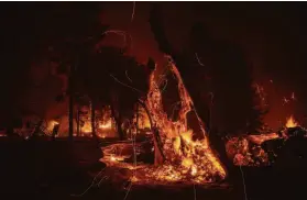  ?? Ethan Swope / Associated Press ?? Trees burn as the Dixie Fire jumps Highway 395 in Lassen County in August.