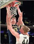  ?? Julie Jacobson / AP ?? Michigan center Jon Teske (back) dunks the ball against Purdue center Isaac Haas on Sunday in New York.