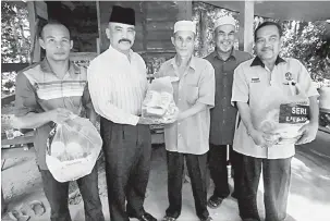  ?? — Gambar Bernama ?? TERIMALAH: Baharin (dua kiri) menyampaik­an bantuan barangan keperluan makanan kepada pesara Mohammad Safar pada Program Santai Dusun Durian Bersama Wartawan Wilayah Utara di Dusun Durian Guar Manau, Padang Perahu dekat Jitra, semalam.