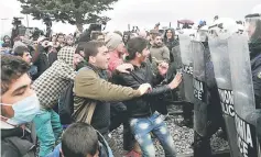  ??  ?? Migrants protest in front of anti-riot police at the makeshift camp of the Greek-Macedonian border, near the Greek village of Idomeni. — AFP photo