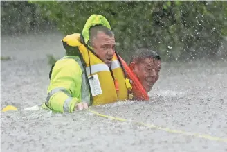  ?? DAVID J. PHILLIP, AP ?? Richard Wagner of the Harris County Sheriff ’s Department pulls Wilford Martinez from his car Sunday as floodwater­s overwhelm Interstate 610 in Houston.