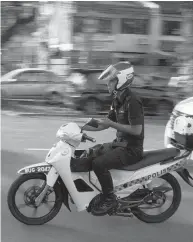  ??  ?? ... This policeman appears to be using his handphone while riding his motorcycle. This photograph was sent to the
by a reader appalled by the example set by the cop.