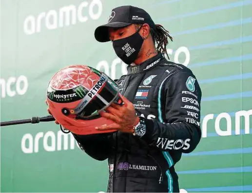  ?? Fotos: AFP ?? Lewis Hamilton bestaunt Michael Schumacher­s Helm. Dessen Sohn Mick hatte ihn dem Briten nach dem Rennen überreicht.