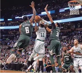  ?? ASSOCIATED PRESS ?? Celtics guard Kyrie Irving drives to the basket between the Bucks’ Eric Bledsoe and John Henson.