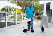  ?? ERIK VERDUZCO/ LAS VEGAS REVIEW-JOURNAL ?? Chris Reyes, behavior and evaluation team member, walks dogs back to their kennels Thursday at the Animal Foundation, which will be changing its operating model.