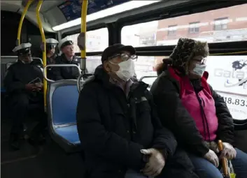  ?? Mark Lennihan/Associated Press ?? Passengers wear masks while riding a city bus Wednesday in Brooklyn. Police have stepped up efforts to pressure New Yorkers to practice social distancing at the epicenter of the crisis.