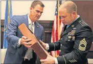  ?? [PHOTO PROVIDED] ?? Gov. Kevin Stitt presents an Oklahoma flag on Wednesday to U.S. Army Master Sgt. Matthew Williams at the state Capitol. Williams, who was awarded the Medal of Honor last month, is scheduled to appear Friday morning at Putnam City West High School.