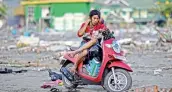  ?? — AFP ?? A survivor rests on his motorbike in Palu in Indonesia’s Central Sulawesi on Wednesday after an earthquake and tsunami hit the area on September 28.