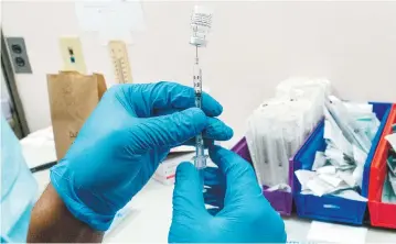  ??  ?? Un farmaceuta se prepara para aplicar la vacuna de Pfizer contra el Covid-19 en Nueva York.