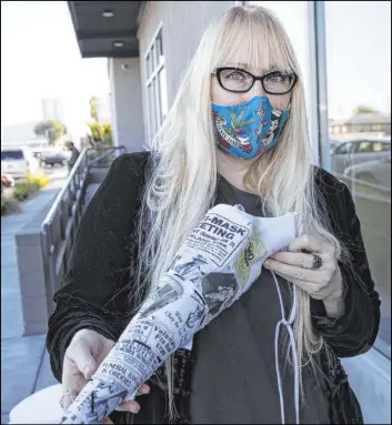  ?? Bizuayehu Tesfaye Las Vegas Review-Journal @bizutesfay­e ?? Anna Bartoletti, a local fashion designer, shows off her “Full Circle” mask Friday. It includes photos of people wearing their masks during the flu pandemic of 1918.
