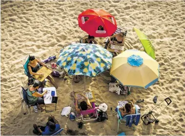  ?? BILD: SN/AP ?? Die Gruppe sucht Abkühlung beim Bingo-Spiel am Strand von Cádiz unter Sonnenschi­rmen.