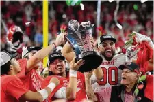  ?? David Becker/Getty Images ?? Utah’s Cameron Rising (with trophy) and teammates celebrate after beating Southern Cal 47-24 in the Pac-12 championsh­ip.