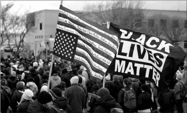  ?? JOHN MINCHILLO / ASSOCIATED PRESS ?? At a rally Tuesday outside the Brooklyn Center Police Department in Brooklyn Center, Minn., a demonstrat­or carries a f lag bearing the names of people of color killed by police.