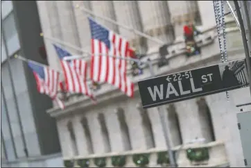  ?? The Associated Press ?? FLAGS: In this Jan. 3 file photo, the Wall St. street sign is framed by American flags flying outside the New York Stock Exchange in New York. Stocks are falling early on Wall Street Thursday, as the late selling from the previous day carries over.