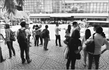  ??  ?? Office workers stand on the grounds of an office building in the financial district of Makati in Manila, after a 5.7 magnitude earthquake. — AFP photo