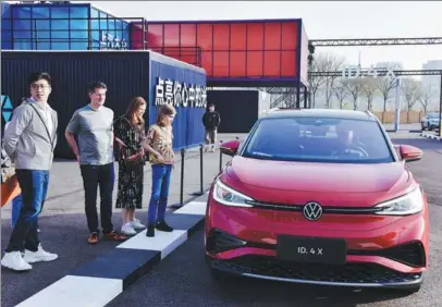  ?? PROVIDED TO CHINA DAILY ?? Visitors check out a Volkswagen EV model during a promotion event in Shanghai in March.