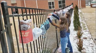  ??  ?? Volunteers place some clothing items at Searcy First United Methodist Church. The church has started a new ministry where anyone can hang new or gently used clothing items on the fence at the church. The items can be picked up by anyone in need.