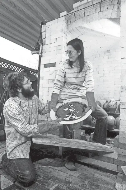  ??  ?? Dale and Brin Baucum at the kiln door in March 1985 prepare for the sixth annual Memphis Potters' Guild show and sale. Dale set up his pottery business here in 1973. THOMAS BUSLER/THE COMMERCIAL APPEAL