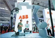  ?? HUANG YONG / FOR CHINA DAILY ?? An employee introduces a robot to a visitor (left) at the exhibition stand of ABB during the 2023 World Robot Conference in Beijing on Aug 18.