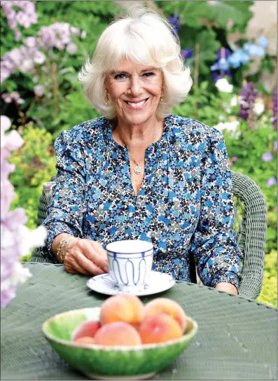  ?? ?? FRUITFUL PORTRAIT: The Duchess of Cornwall in her country garden, with a bowl of home-grown peaches