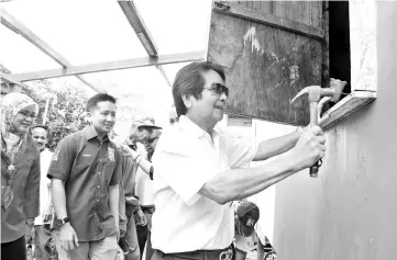  ??  ?? Kurup repairing a house at Kampung Panagatan Laut in Sook yesterday.