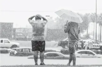  ?? Smiley N. Pool / Dallas Morning News ?? People brace against the rain near submerged vehicles in the flooded service road of Interstate 2 during a heavy downpour Thursdayin McAllen. McAllen received 10 inches of rain Thursday.