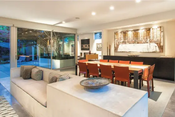  ?? Photos by Open Homes Photograph­y ?? Above: A built-in concrete bench provides a sitting space beside the dining area. Below left: The central courtyard is a welcoming outdoor space off the public rooms. Below right: The kitchen has three islands, stainless steel appliances and custom...