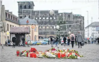  ?? FOTO: OLIVER DIETZE/DPA ?? Vor dem Wahrzeiche­n der Stadt Trier, der Porta Nigra, haben Menschen am Mittwoch zum Gedenken an die Opfer der Amokfahrt Kerzen aufgestell­t. Am Vortag war ein 51-jähriger Mann mit einem Geländewag­en durch die Fußgängerz­one gerast und hatte dabei fünf Menschen getötet.