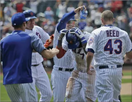  ?? SETH WENIG — THE ASSOCIATED PRESS ?? New York Mets' Jose Reyes, center, is mobbed by teammates after hitting a walk-off RBI single during the ninth inning of a baseball game against the St. Louis Cardinals at Citi Field, Thursday in New York. The Mets defeated the Cardinals 3-2.