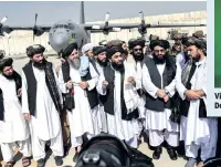  ??  ?? Taliban spokesman Zabihullah Mujahid (in the centre with shawl) speaks to the media at the airport in Kabul