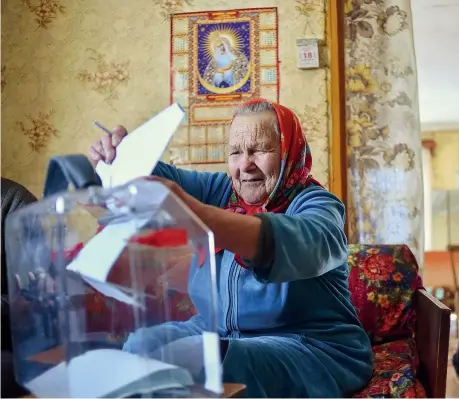  ??  ?? La giornata elettorale A sinistra, una donna anziana esprime il suo voto in casa, nel villaggio di Khrapovo, a sudovest di Mosca (Afp/ Sergei Gapon). Sopra, alcuni nuotatori si tuffano nell’acque gelide tenendo in bella mostra una bandiera della Russia...