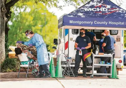  ?? Mark Mulligan / Staff photograph­er ?? Montgomery County Hospital District paramedics conduct COVID-19 tests outside Focused Care at Beechnut in Houston.