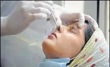  ?? PTI ?? A health worker collects a swab sample of a woman at the civil hospital in Amritsar on Tuesday.