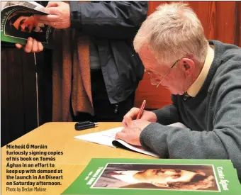  ?? Photo by Declan Malone ?? Micheál Ó Moráin furiously signing copies of his book on Tomás Ághas in an effort to keep up with demand at the launch in An Díseart on Saturday afternoon.