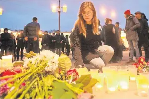  ?? AP PHOTO ?? A woman lights a candle at an entrance to Sennaya subway station after an explosion killed 11 people on the subway in St. Petersburg, Russia, Monday.