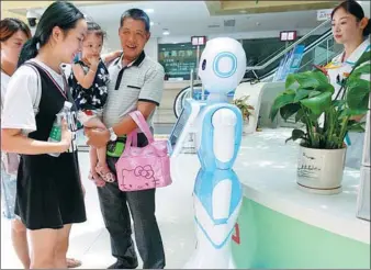  ?? WANG BIAO / FOR CHINA DAILY ?? Visitors interact with a robot guide at Fuyang Women and Children Hospital in Fuyang, Anhui province, on Aug 2.