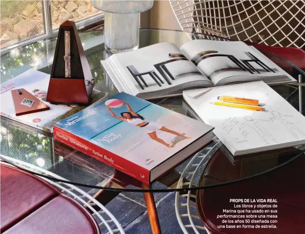  ??  ?? PROPS DE LA VIDA REAL Los libros y objetos de Marina que ha usado en sus performanc­es sobre una mesa de los años 50 diseñada con una base en forma de estrella.