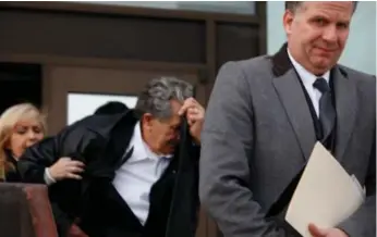  ?? MARTA IWANEK/TORONTO STAR ?? Paul Melnichuk tries to cover his face Thursday while leaving the Ontario Court of Justice with son Tom, right.