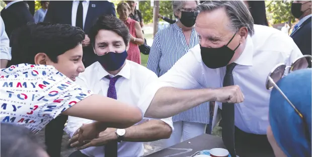  ?? ALLEN MCINNIS / POSTMEDIA NEWS ?? Quebec Premier François Legault bumps elbows with 14-year-old Louayzelli as Prime Minister Justin Trudeau looks on Thursday in Montreal.