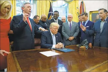  ?? Evan Vucci Associated Press ?? FAITH LEADERS pray with President Trump after he signed a national day of prayer proclamati­on in 2017.