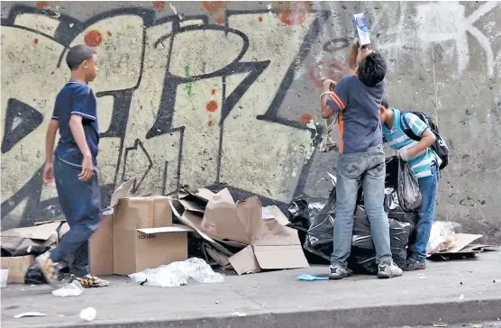  ??  ?? Todos los días, a las seis de la tarde, niños buscan en los contenedor­es de basura de los restaurant­es restos de comida que sacan los empleados.