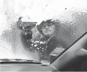  ?? STEPHEN B. MORTON/AP ?? Omar Elkhalidi scrapes ice off his windshield in Savannah, Ga., on Wednesday. Snow fell in the city for the first time since 2010.