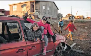  ??  ?? Local kids play in a wrecked van in the town of Gjoa Haven, Nunavut.